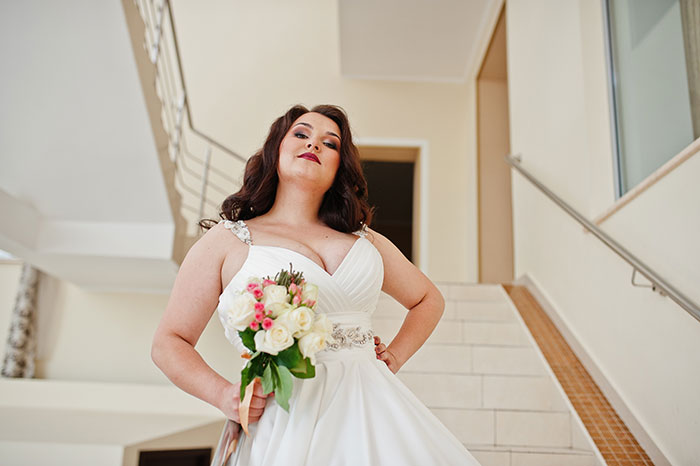 Mujer con vestido de novia con ramo, parado en las escaleras, simbolizando las preocupaciones de salud y el conflicto de la foto estética de la boda.