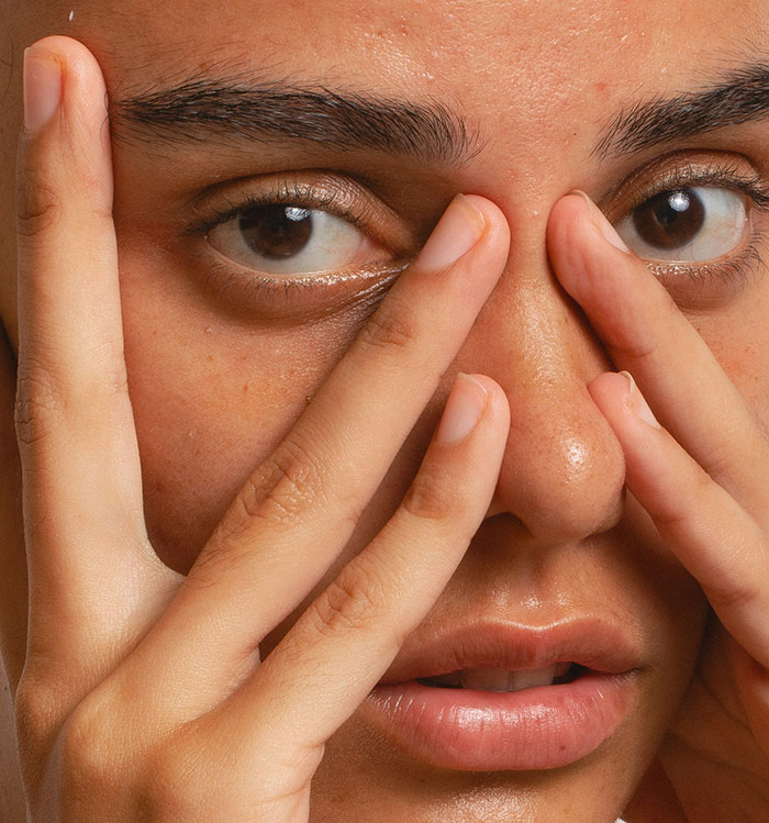 Primer plano de la mujer tocando su rostro, expresando preocupación por negarse a arriesgar la salud de la estética de la foto de la boda de la hermana.