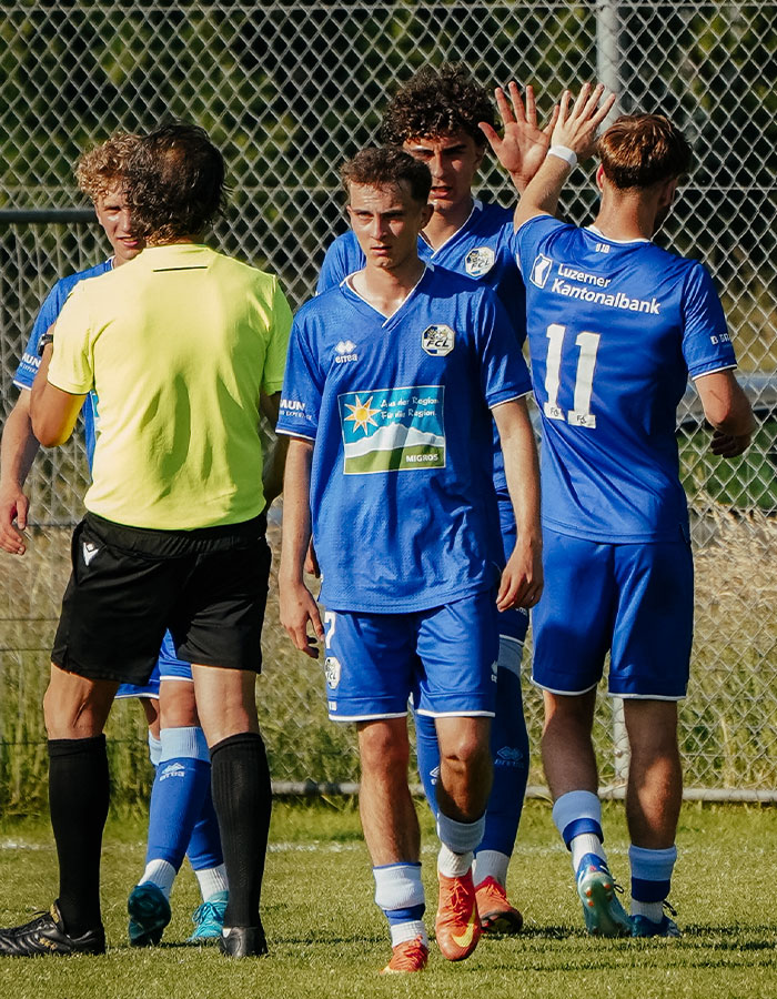 Equipo de fútbol masculino U15 celebrando en el campo tras partido contra el equipo nacional de fútbol femenino, mostrando el trabajo en equipo y la deportividad