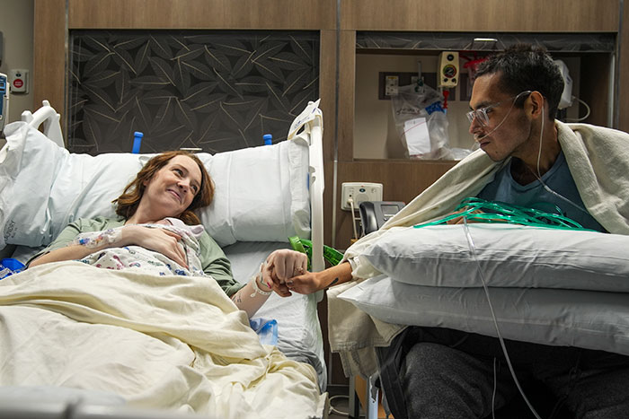 Tanner Martin en la cama del hospital tomados de la mano con una mujer, reflexionando sobre su paso días después de que su bebé nació en video pregrabado.