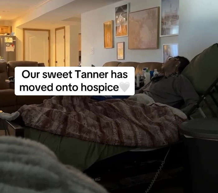 Hombre acostado en una cama en casa con un mensaje de texto sobre Tanner Martin pasando a Hospice Care después de su anuncio de aprobación a los 30.