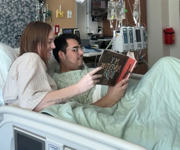 Tanner Martin en la cama del hospital leyendo un libro con una mujer, anunciando su propio fallecimiento en un video pregrabado.