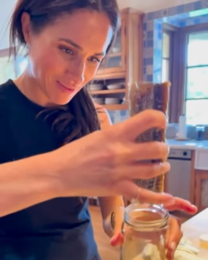 Meghan Markle preparando comida en una cocina, destacando la conexión de su marca con los productos Williams Sonoma.