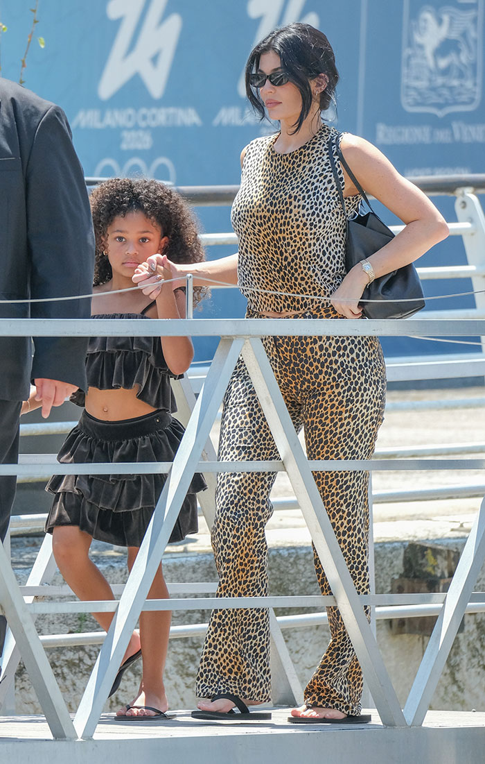 Celebridades en atuendo de estampado de leopardo y gafas de sol caminando con un niño, exhibiendo el evento de celebridades de la celebridad de la fiesta después del evento de fiesta de fin de semana.