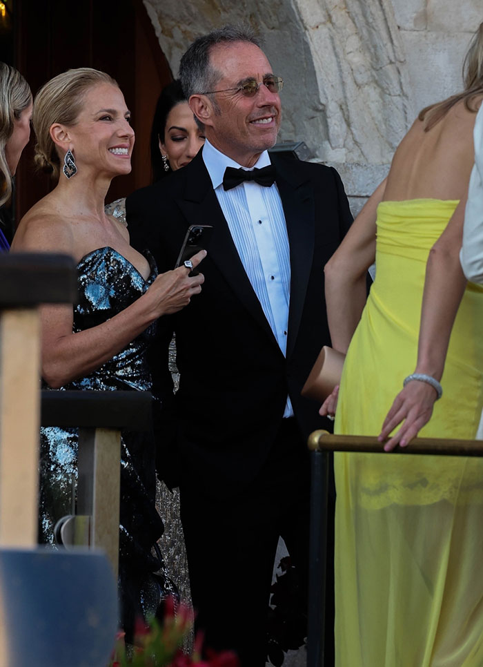 Celebrity Strunging mira una fiesta de bodas, vestida con atuendo formal, socializando después de las celebraciones de fin de semana.