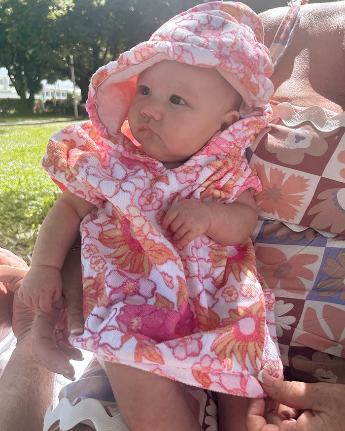 Baby de 5 meses con toalla floral con capucha al aire libre, que representa el incidente de broma de extinción de incendios que los adolescentes salieron mal.