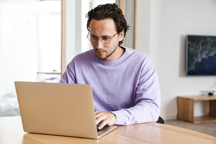 El hombre con gafas y suéter morado se centró en la computadora portátil, que representa a los empleados sin fines de lucro acusados ​​de fusionar horas.