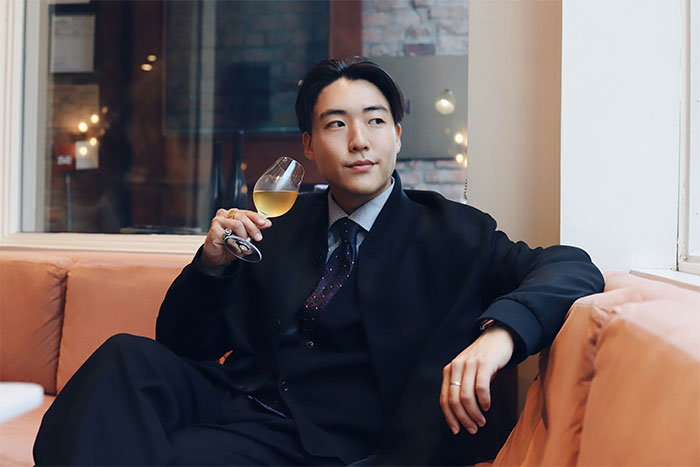 El hombre en traje que tiene una copa de vino, relajándose en un sofá, que representa a la compañía de seguros niega el impacto de reclamo de empleados.