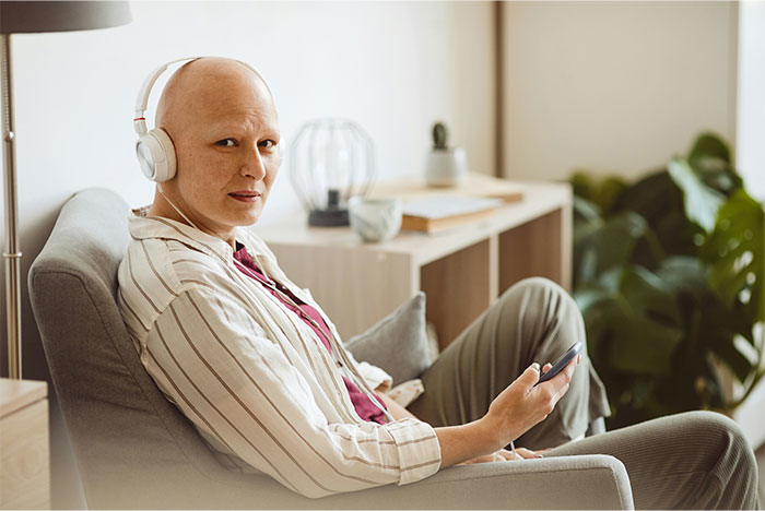 Persona con auriculares, que aparece contemplativo, sentado en el interior sosteniendo un teléfono, relacionado con la palabra clave falsa de exposición al cáncer.