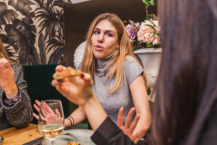 Mujer frustrada durante la cena familiar aplaudiendo a la prima insultando su estado de boda y relación