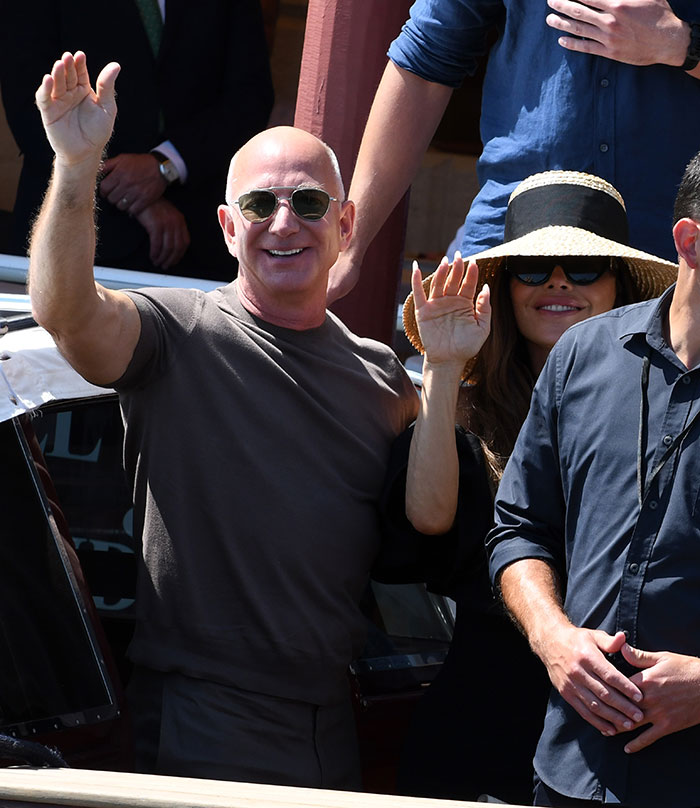 Jeff Bezos y Lauren Sánchez saludan mientras asistían a un evento de celebridades después de la fiesta de la boda de fin de semana.