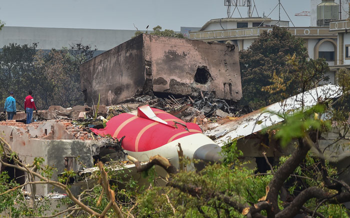 Los restos de un sitio de accidente aéreo con escombros y estructuras quemadas mientras los investigadores encuestan el área después del accidente.