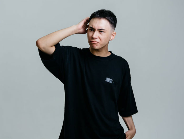 Young Man con camisa negra con expresión frustrada, que representa un conflicto sobre los regalos de Brother de Golden Child.
