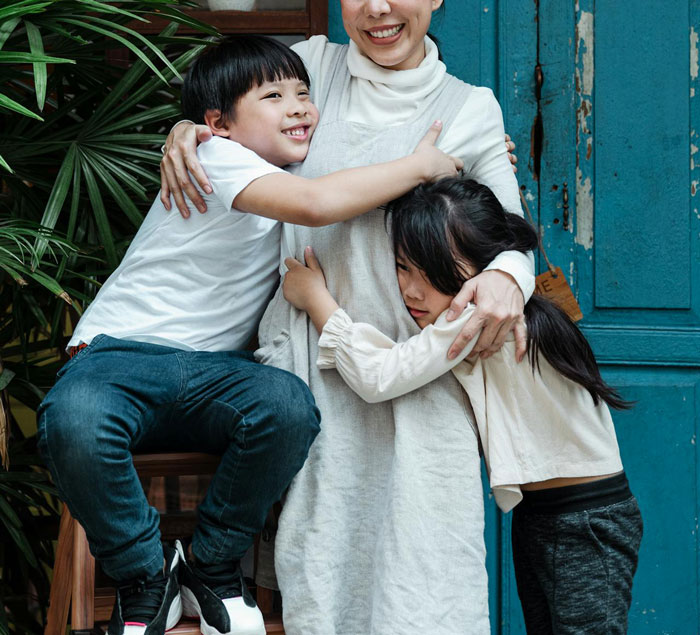 El joven abraza a la madre sonriendo mientras la niña se aferra tristemente, ilustrando el conflicto de regalos del hermano dorado que roba el hermano.