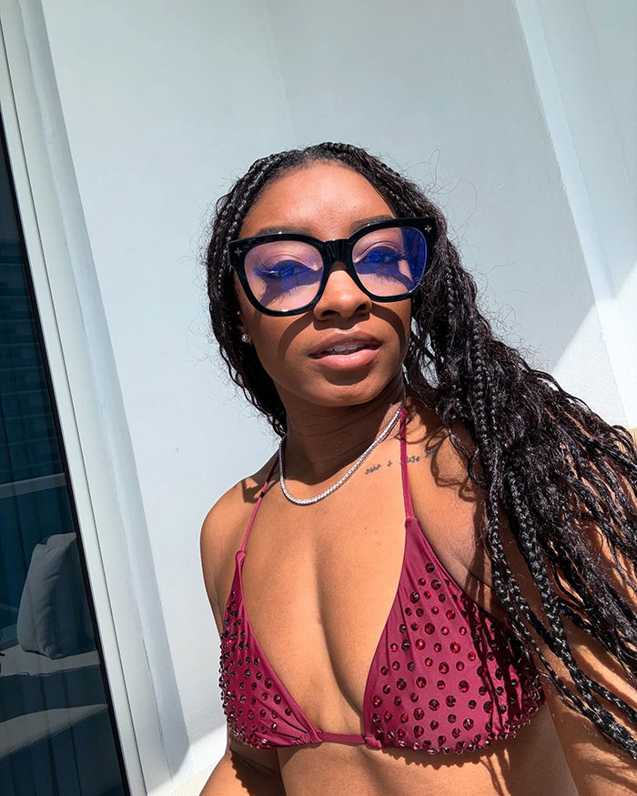 Simone Biles con vasos grandes y una parte superior de bikini tachonado de marrón, provocando cirugía plástica y rumores de jubilación de vacaciones.