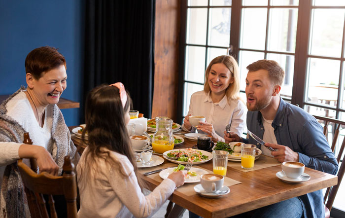 Familia disfruta de una comida juntos en una mesa de madera, destacando las alergias de los hermanastros que afectan las opciones de alimentos de cumpleaños
