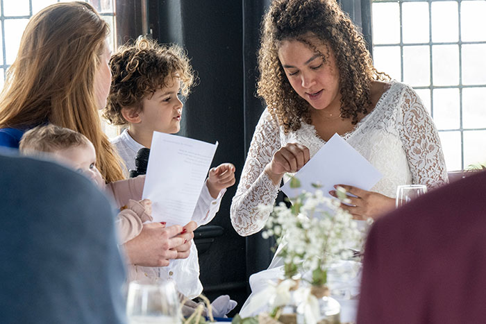 Novia con un vestido de encaje blanco que interactúa con invitados en una boda, reflexionando sobre neutros y opciones de color.