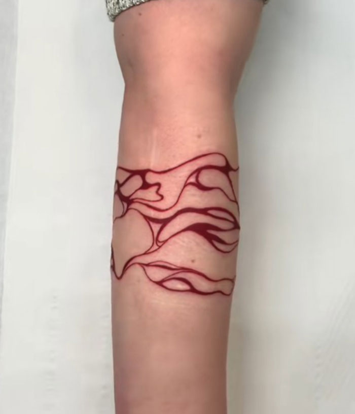 Diseño de encubrimiento de tatuaje rojo abstracto en el antebrazo interno por artista de tatuajes conocido por los encubrimientos virales.