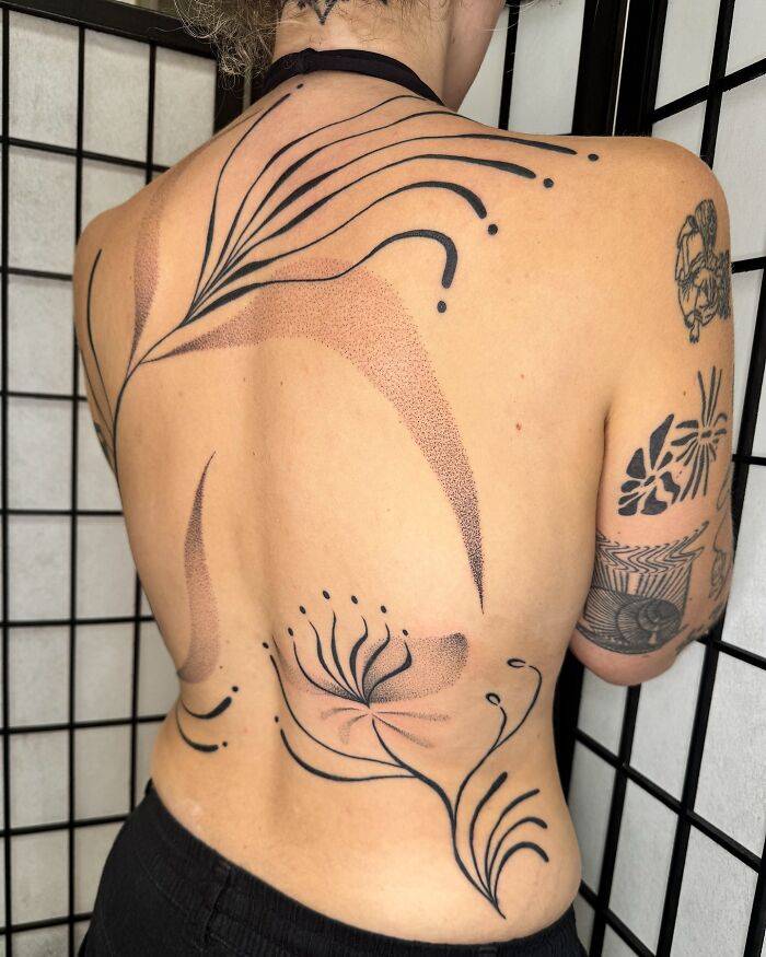 Tatuaje abstracto de encubrimiento negro y dotwork en la espalda de una persona por un artista de tatuajes que obtiene atención viral.