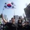 La gente reacciona después de escuchar la noticia de que el presidente Yoon Suk Yeol fue retirado del cargo, en Seúl, Corea del Sur, el viernes 4 de abril de 2025.
