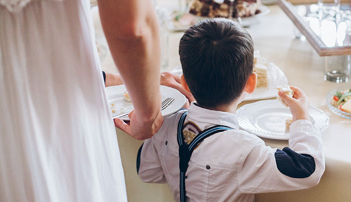 Novia de pie junto al sobrino autista en una mesa de bodas, destacando el conflicto familiar sobre la inclusión y la aceptación.