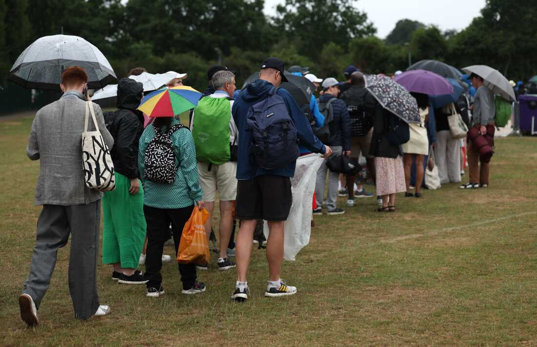 Los espectadores hacen cola bajo paraguas mientras llueve el tercer día en Wimbledon, el 2 de julio.