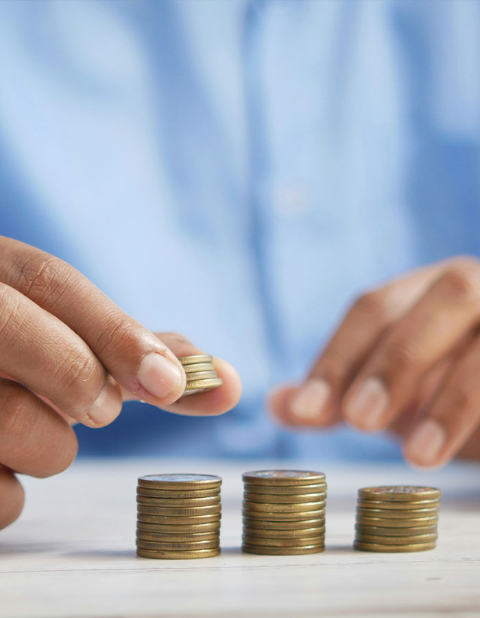 Primer plano de una persona apilando monedas que representan el control financiero y el ego masculino en la administración del dinero.
