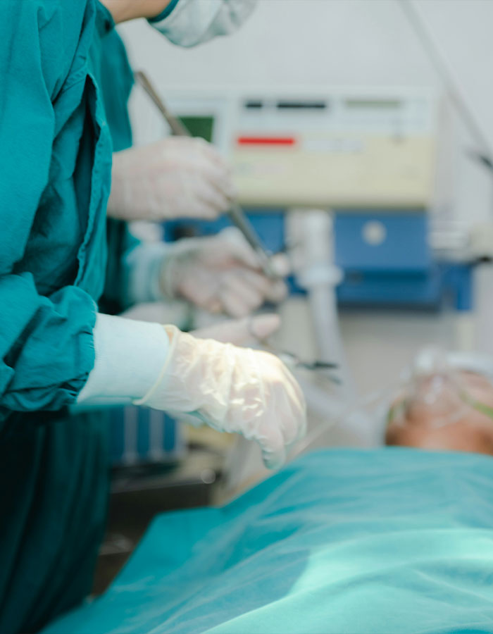 La tecnología de la autopsia con guantes que realizan un examen en un entorno médico con paciente sobre la mesa.