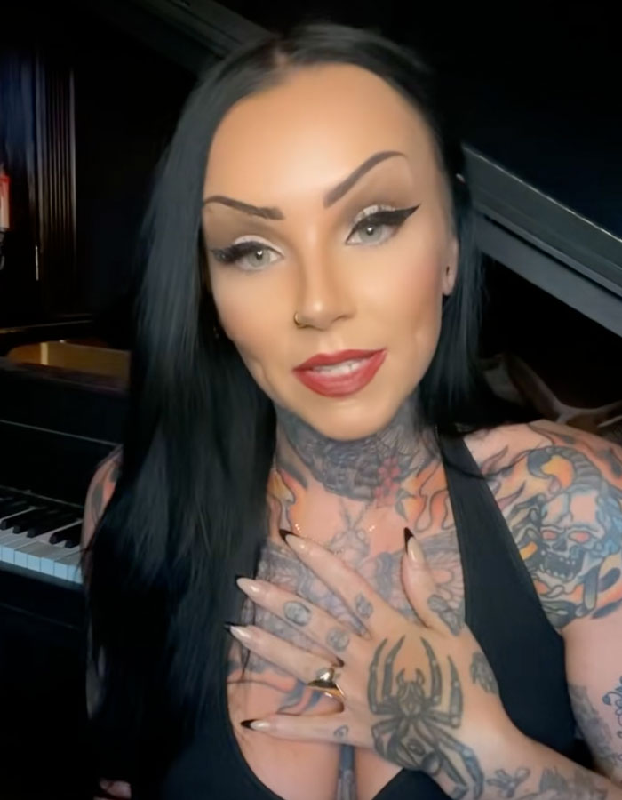 Mujer joven con tatuajes, con un top negro, compartiendo ideas sobre tecnología de autopsia y formas extrañas en las que las personas han fallecido.