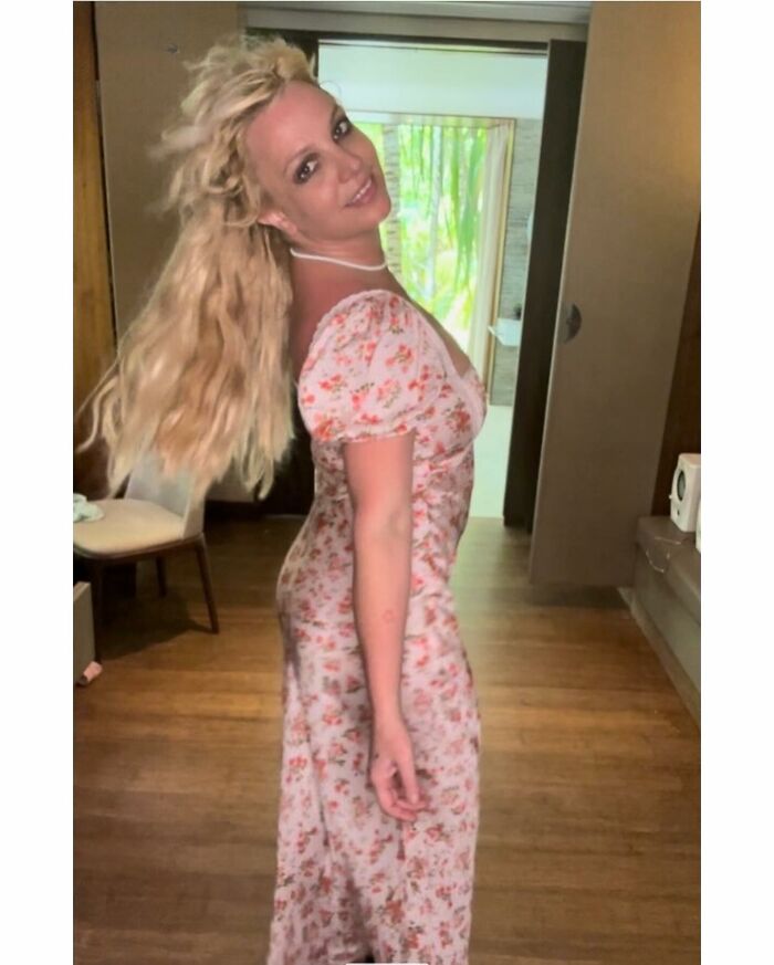 Britney Spears sonriendo en interiores con un vestido floral, desgastando frenesí después de anunciar la adopción de una niña.