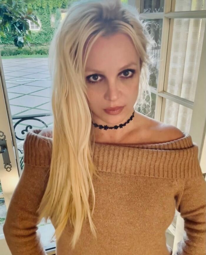 Britney lanza en el interior con un suéter marrón y una gargantilla negra, provocando frenesí después de adoptar una niña.