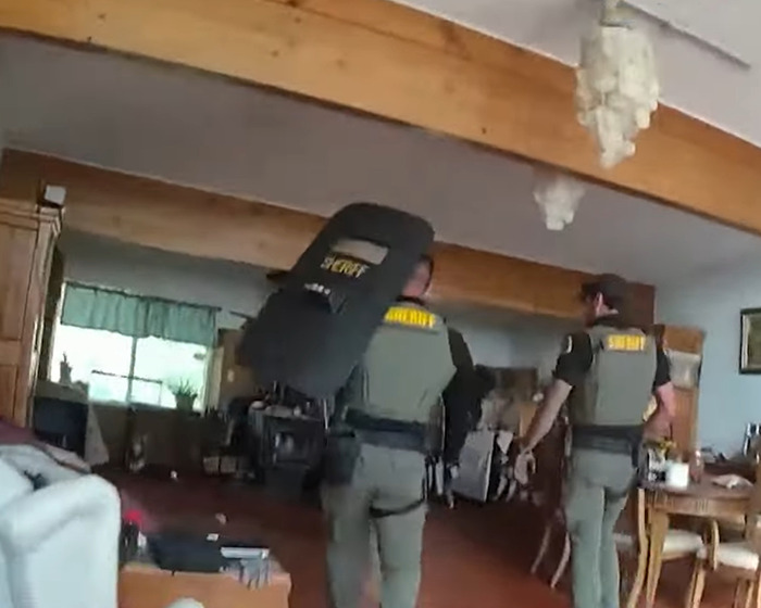 Dos oficiales del sheriff dentro de una casa que investiga la horrible escena de un incidente familiar de matar.
