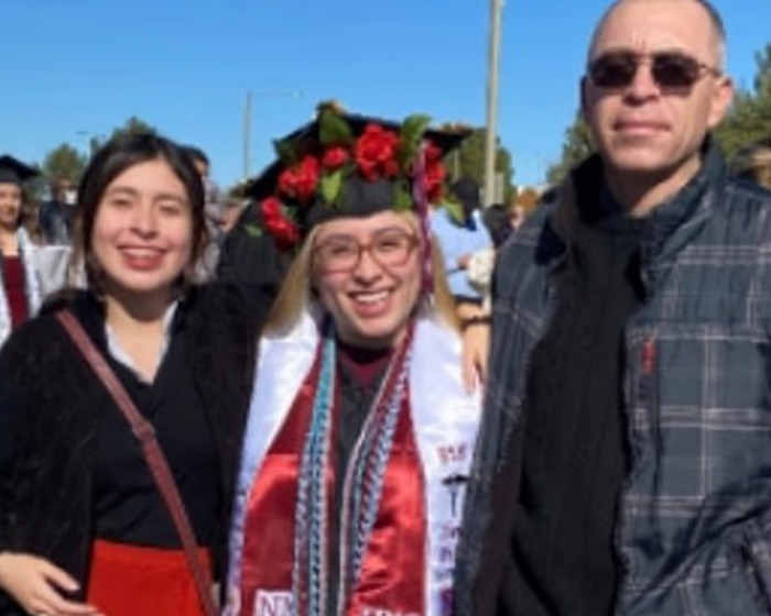 Tres personas sonriendo al aire libre, con una mujer con atuendo de graduación, no relacionadas con el hombre matrices de noticias de perros familiares.