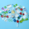 Varias piezas de basura colorida, como tapas de botellas de plástico y horquillas de plásticos, están dispuestas en forma de cerebro humano, sobre un fondo azul claro.