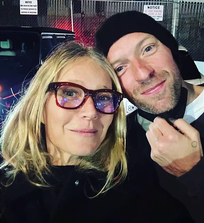Gwyneth Paltrow Selfie de primer plano con un hombre que lleva un gorro negro afuera por la noche cerca de una zona de estacionamiento.