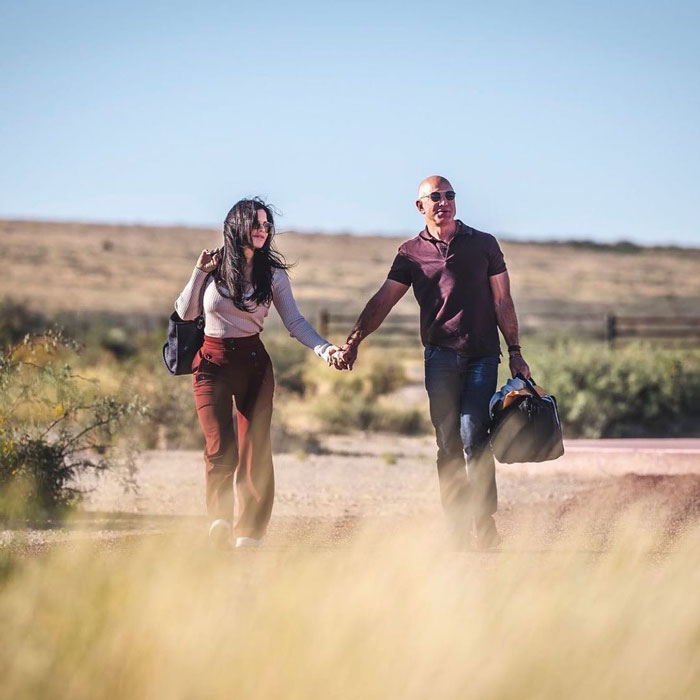 Jeff Bezos caminando de la mano con Lauren Sánchez en un escenario del desierto, mostrando su aspecto cambiado de cabello.