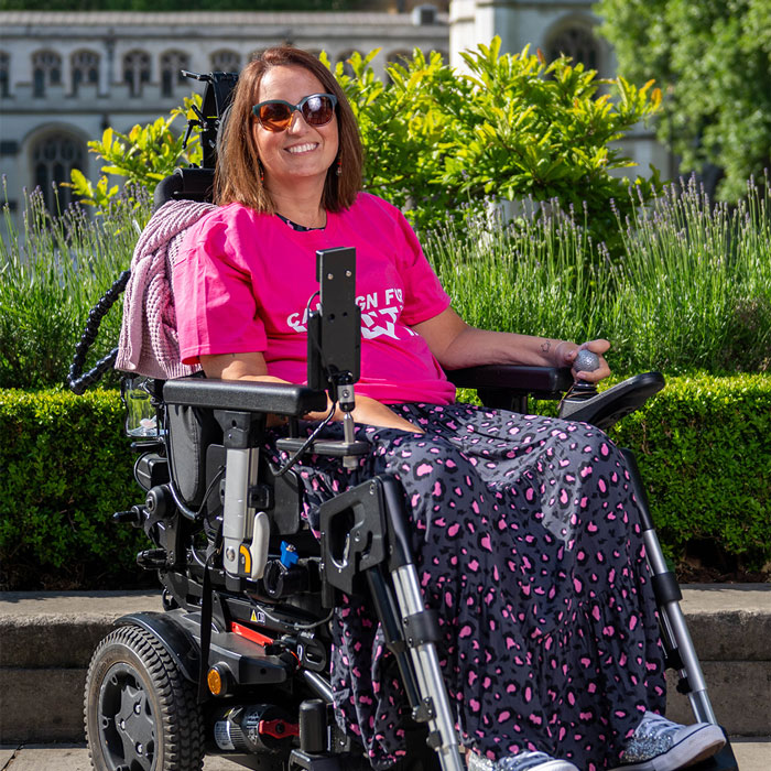 Mujer en una silla de ruedas al aire libre sonriendo, que representa un grupo de apoyo después de que la mujer terminó su propia vida de hambre.