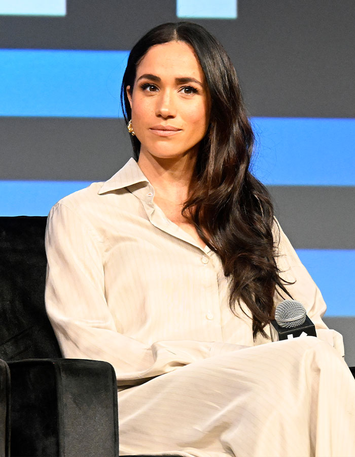 Mujer con cabello largo y oscuro con una blusa crema sentada, relacionada con el ex evento de noticias de Kate Middleton, Asistente y Meghan Markle.