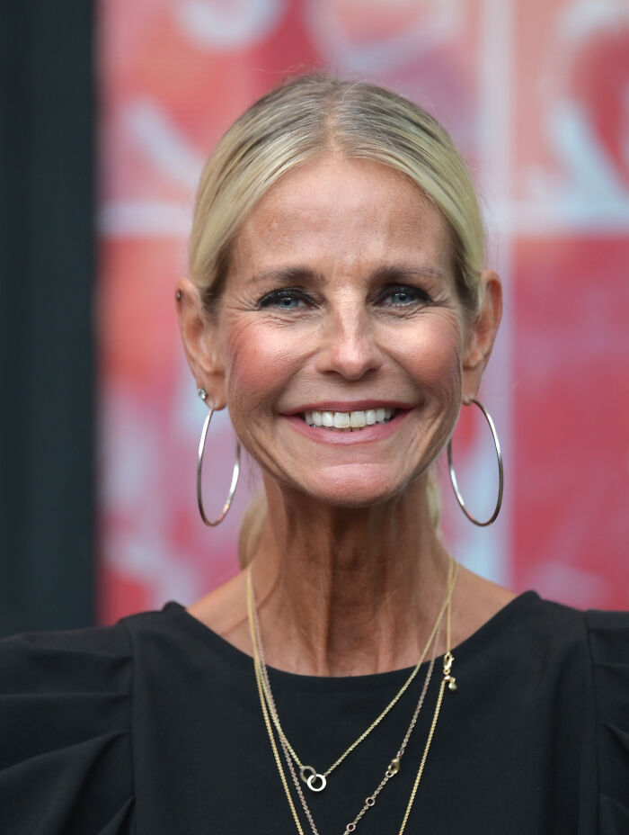 Ulrika Jonsson sonriendo con aretes de aro y collares en capas, que se dirige a trolls sobre su rostro demasiado tanqueado en línea.