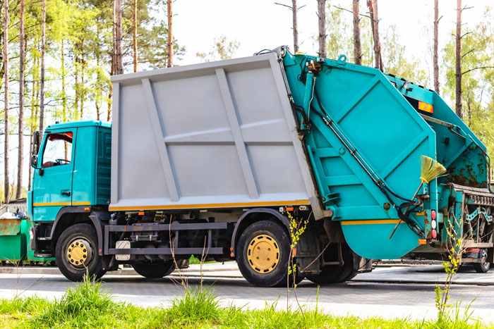 El camión de basura estacionó al aire libre cerca de los árboles y la hierba, que representa la gaviota de California enganchando un viaje de 80 millas.