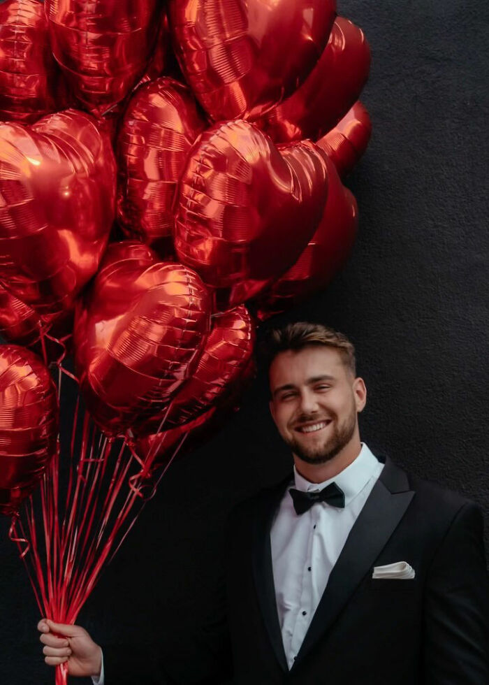 Hombre en esmoquin con globos rojos en forma de corazón, relacionado con la campaña de correo electrónico de Netflix dirigida a mujeres hasta la fecha de Aussie Star