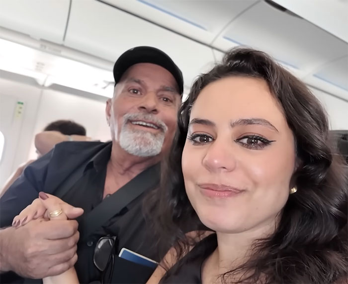 Mujer y hombre mayor sonriendo juntos en el avión, capturando el momento de visita a la casa familiar después de muchos años.