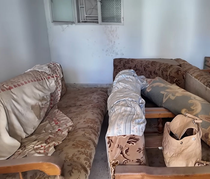 Interior de la casa familiar antigua con sofás desgastados y una bolsa, simbolizando la visita de una mujer 46 años después de que papá se fue.