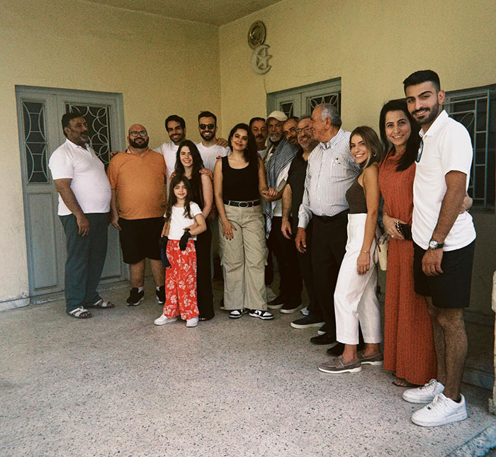 Gran grupo familiar de pie juntos en una casa familiar durante la visita de una mujer 46 años después de que su padre se fue.
