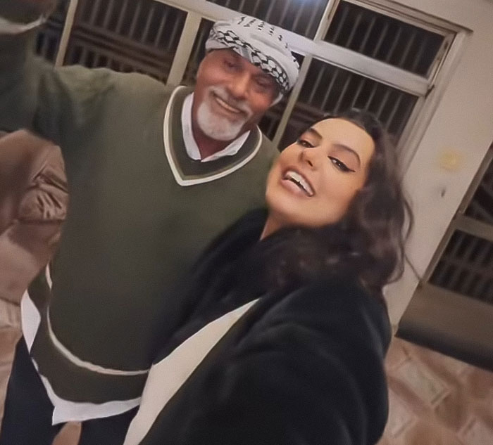 Mujer sonriendo con un hombre mayor dentro de la casa familiar durante la visita emocional 46 años después de que papá se fue, capturando un impresionante momento de reunión.