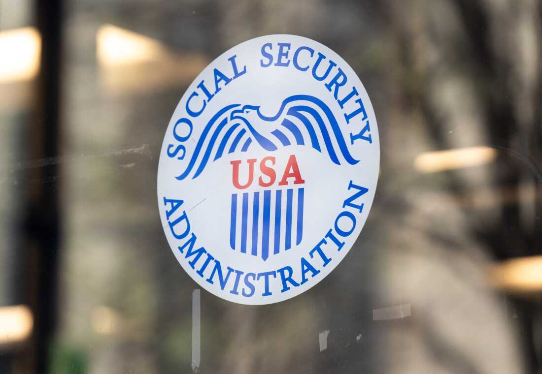 Esta foto muestra el logotipo de la Administración del Seguro Social en una ventana de vidrio de una oficina de la Administración del Seguro Social en Washington, DC, en marzo. El logotipo blanco redondo presenta un águila azul, las letras