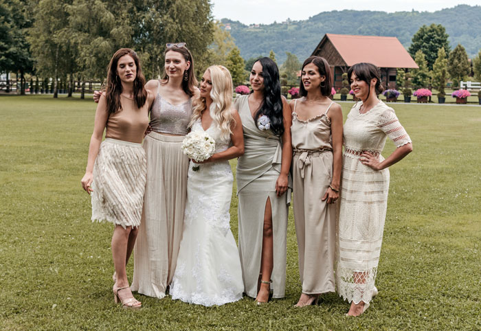 Novias y damas de honor con vestidos neutros al aire libre, destacando el contraste con la expectativa de usar color.