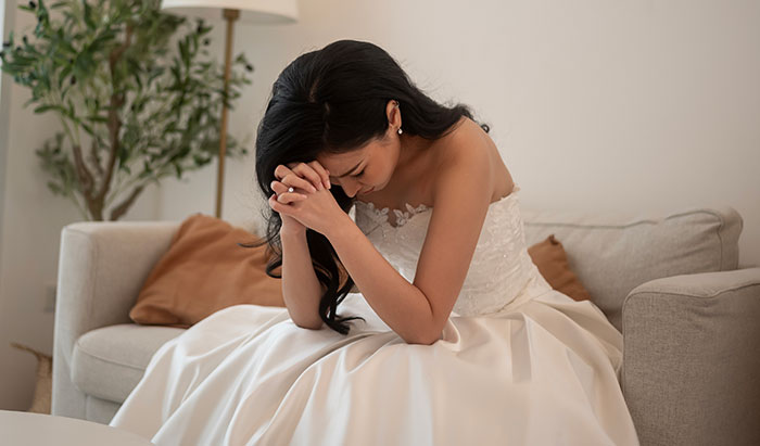 Novia con el vestido de novia sentado en el sofá molesto después de que los padres de los novios llaman a su mocoso egocéntrico por no patear sobrino autista