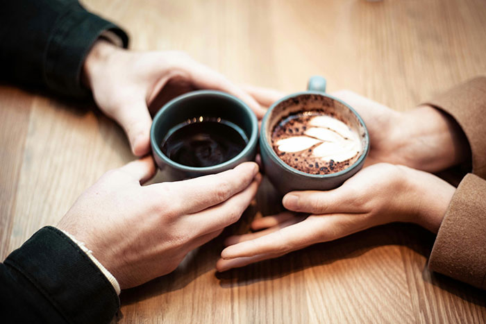 Dos personas que mantienen tazas de café juntas simbolizando la relación y el retraso del divorcio después de la pérdida de la pareja de asuntos en el choque.