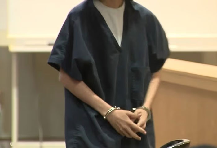 Mujer con uniforme de prisión oscura con esposas, según los informes, involucrados en ayudar a su hijo a planificar el tiroteo en la escuela masiva.